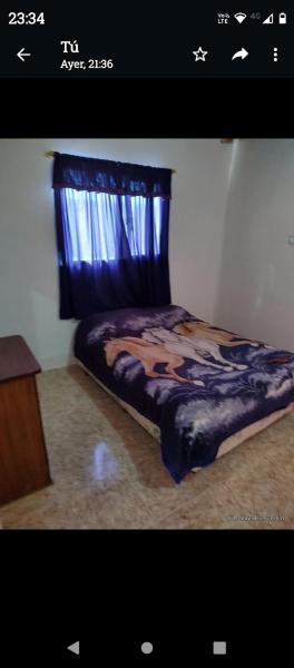 1 dormitorio con 1 cama con edredón azul y ventana en CELRIOS Departamento en Puerto Madryn