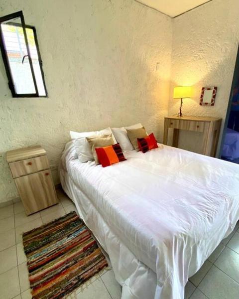 1 dormitorio con 1 cama blanca grande con almohadas rojas en Duplex con terraza y estacionamiento p auto! en Mendoza