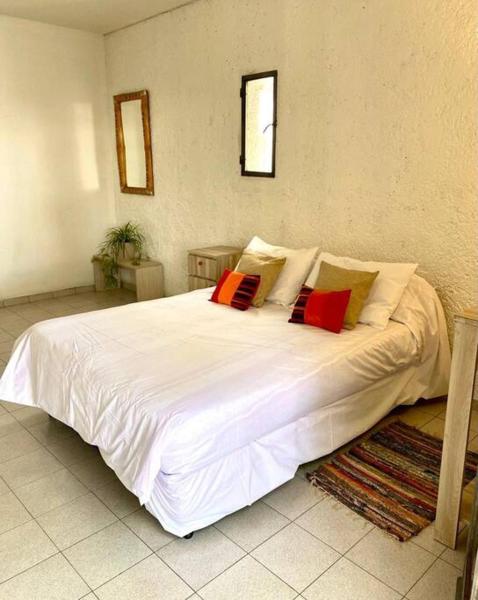 1 dormitorio con 1 cama blanca grande con almohadas rojas en Duplex con terraza y estacionamiento p auto! en Mendoza