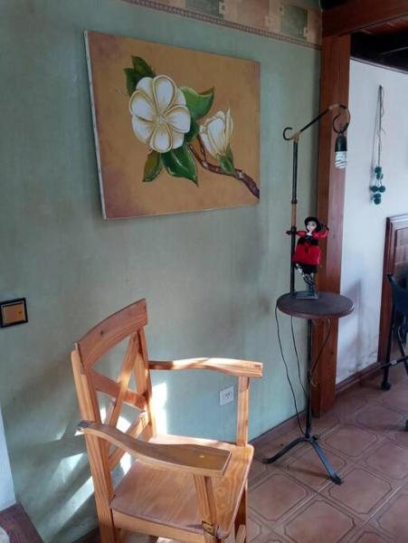 una silla de madera en una habitación con una foto en la pared en Villa Cristina en Chascomús