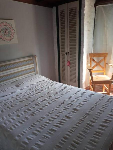 1 cama blanca en un dormitorio con silla en Villa Cristina en Chascomús