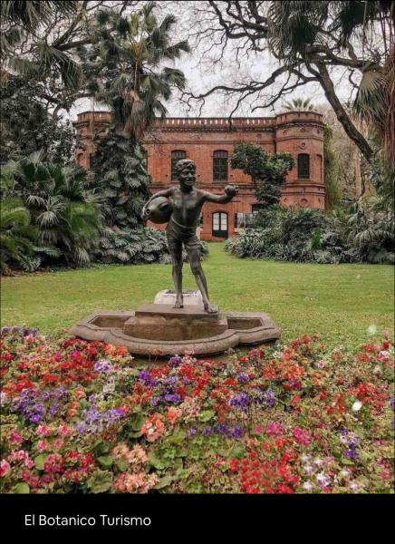 una estatua en un jardín con flores frente a un edificio en Departamento ideal para tu paso por Buenos Aires en Buenos Aires