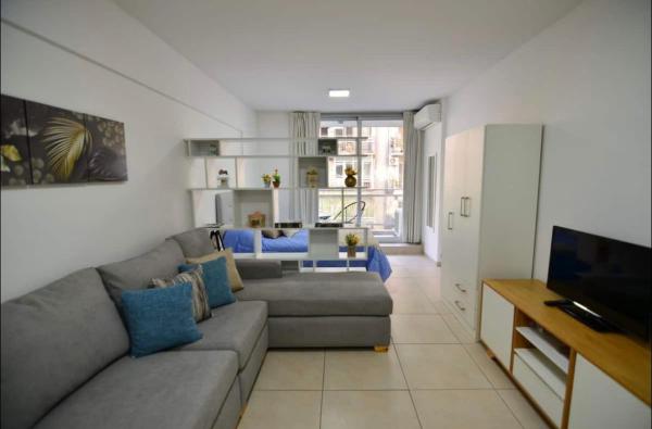 sala de estar con sofá y TV en Departamento ideal para tu paso por Buenos Aires en Buenos Aires