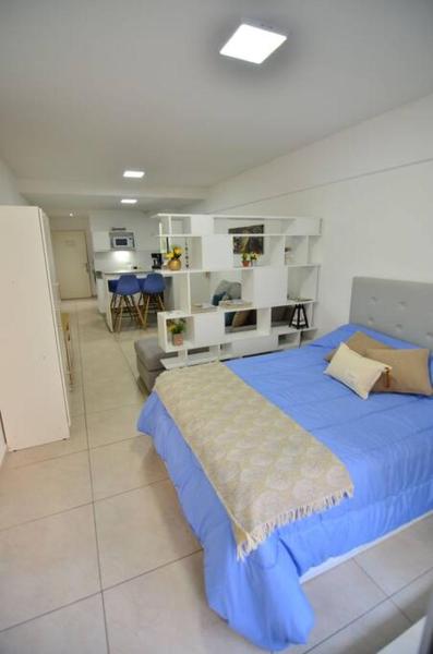 1 dormitorio con 1 cama azul y sala de estar en Departamento ideal para tu paso por Buenos Aires en Buenos Aires