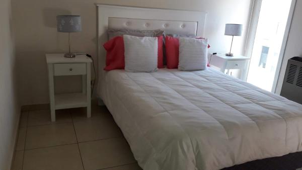 1 dormitorio con 1 cama grande con almohadas rojas y blancas en Cristal en Tandil