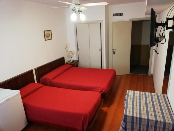 Habitación con 2 camas rojas en una habitación en Necochea Real Hotel en Necochea