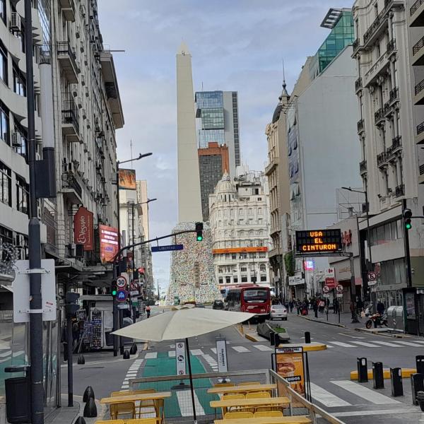 una calle con sillas y una sombrilla en una ciudad en Apartamento todo entero en Buenos Aires