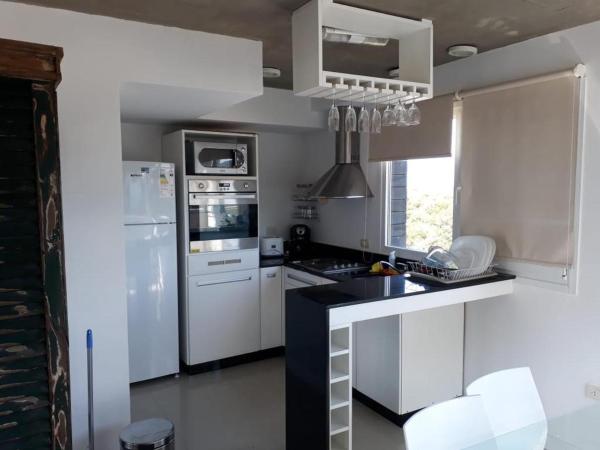cocina con electrodomésticos blancos y encimera negra en Linda Bay Beach & Resort en Mar de las Pampas