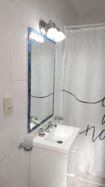 Baño blanco con lavabo y espejo en DEPARTAMENTOS MENDOZA PEATONAL 2 en Mendoza