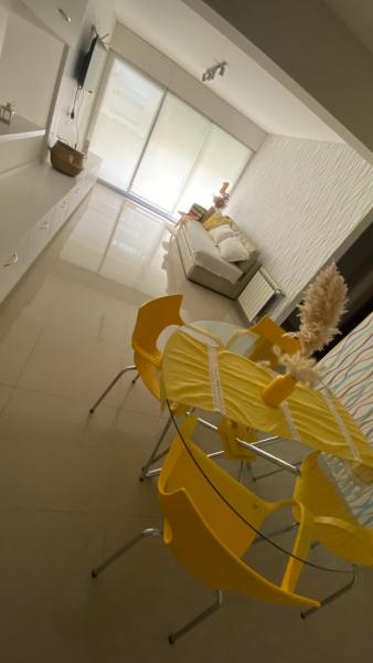 Habitación con silla amarilla y sofá en Departamento TIERRA VI en Salta