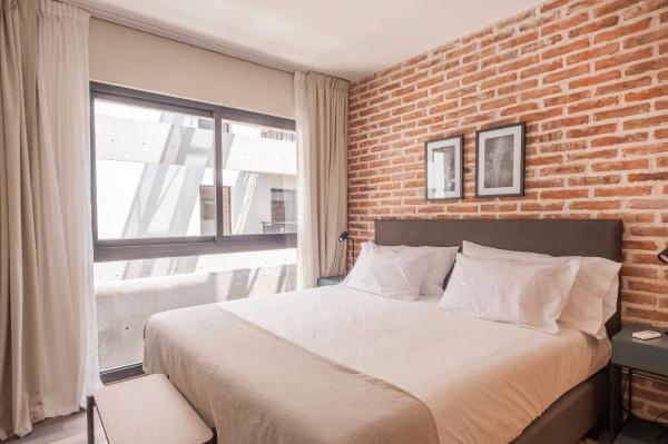 1 dormitorio con 1 cama grande y pared de ladrillo en Descubrí BA en este Increíble Depto @ San Telmo - 225 - en Buenos Aires