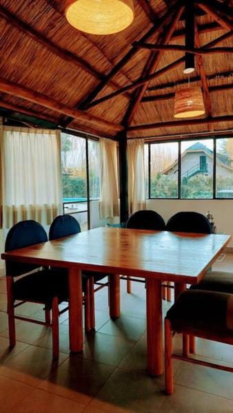 una mesa de madera y sillas en una habitación con ventanas en Fabulosa y confortable cabaña en Mendoza