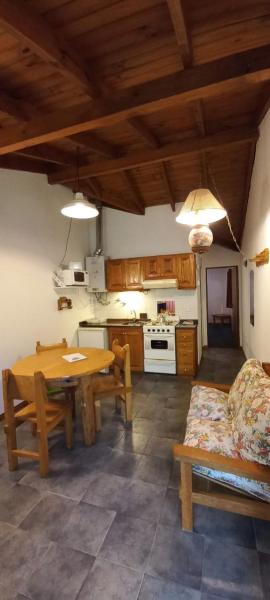 sala de estar con mesa de madera y cocina en Complejo Ciprés en San Martín de los Andes