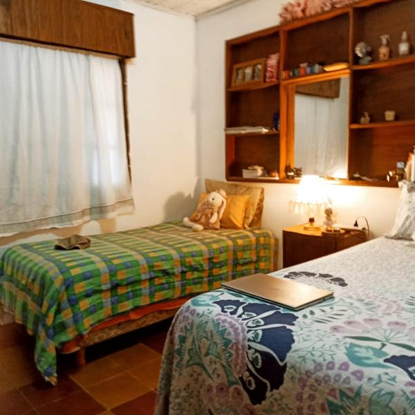 1 dormitorio con 2 camas y un osito de peluche sentado en un banco en La casita de Armi en Gualeguaychú