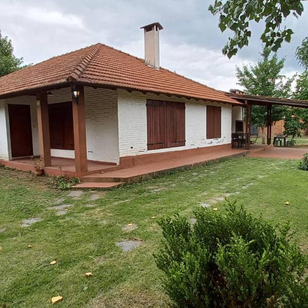 una pequeña casa blanca con un patio de césped en Cabañas Tres Ríos Vacacional en Villa Cura Brochero