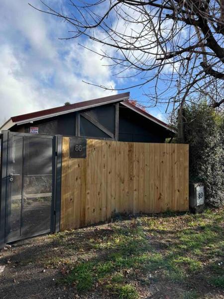 una casa con una valla de madera y una puerta en el ranchito en San Martín de los Andes