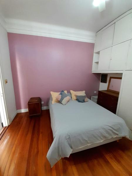 1 dormitorio con cama blanca y pared morada en Arrabalera en Buenos Aires