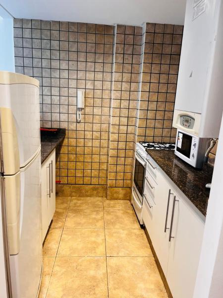 una pequeña cocina con armarios blancos y refrigerador. en Departamento a metros Paseo Balcarce en Salta