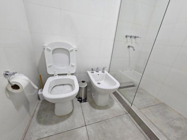 y baño blanco con aseo y ducha. en Departamento de categoría en Salta Capital en Salta
