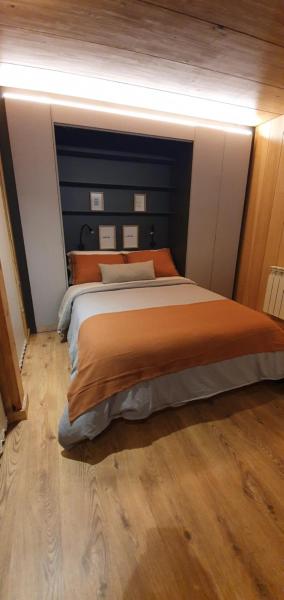 1 dormitorio con 1 cama grande con sábanas de color naranja en Hermoso monoambiente de diseño único, con patio, en el centro de SMA. 4v5 en San Martín de los Andes