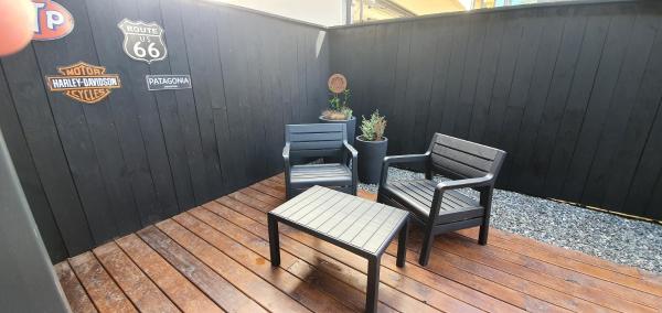2 sillas y una mesa en una terraza de madera en Hermoso monoambiente de diseño único, con patio, en el centro de SMA. 4v5 en San Martín de los Andes