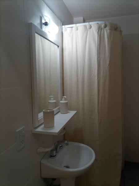 Baño blanco con lavabo y espejo en Departamento Victoria en Buenos Aires