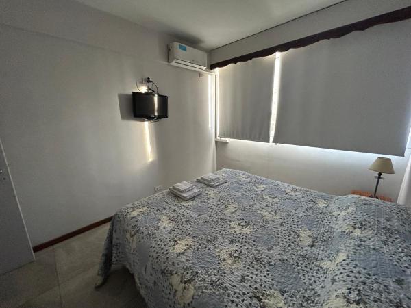 1 dormitorio con 1 cama y TV en la pared en Depto Céntrico a Estrenar con cochera propia en Mendoza