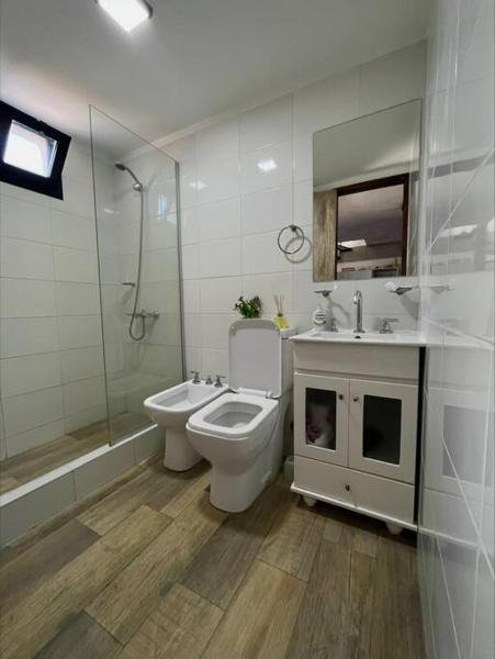 y baño con aseo, lavabo y ducha. en Monoambiente vista lateral en Pinamar en Pinamar