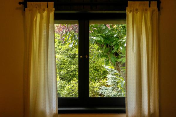 una ventana con cortinas y vistas al jardín en Hosteria Dalmacia en Pinamar