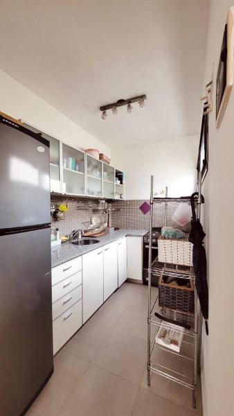 cocina con armarios blancos y refrigerador de acero inoxidable en Cozy and sunny apartment in the saavedra neighborhood en Buenos Aires