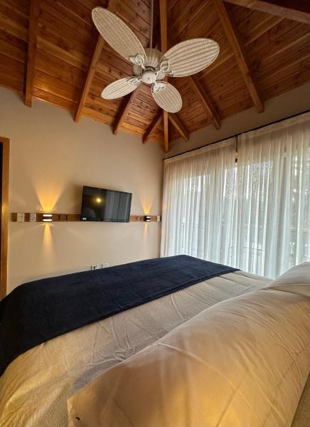 1 dormitorio con ventilador de techo y 1 cama en TERRAZAS DEL MASCARDI - LUXURY APARTMENT - INMEJORABLE UBICACION en San Martín de los Andes