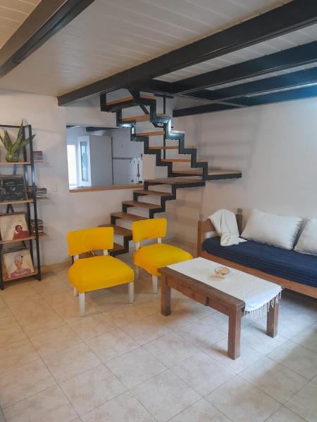 sala de estar con escalera, sofá y sillas en Departamento Costanera en Gualeguaychú
