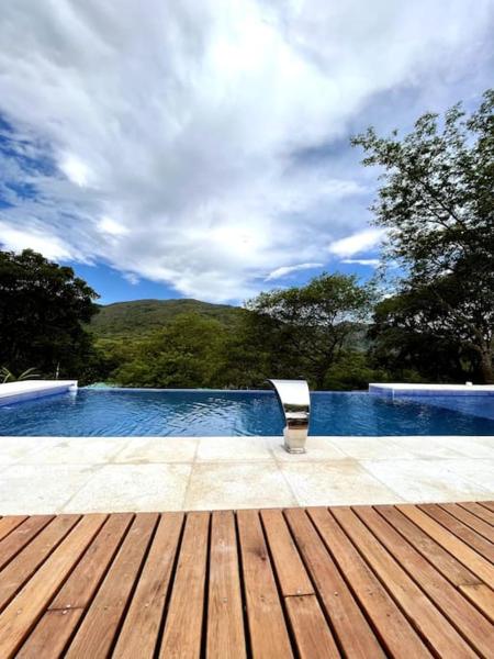 un banco sentado en una terraza de madera junto a una piscina en Casa Quincho ROMA en Salta