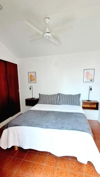1 dormitorio con 1 cama grande y ventilador de techo en Duplex Besugo en Pinamar