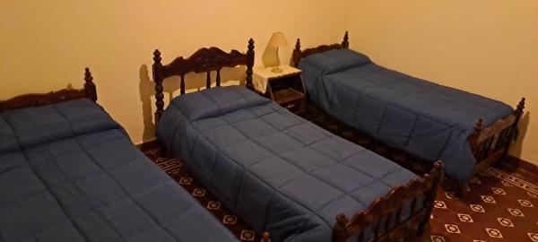 Tres camas en una habitación con mantas azules. en Casa Linda en Salta
