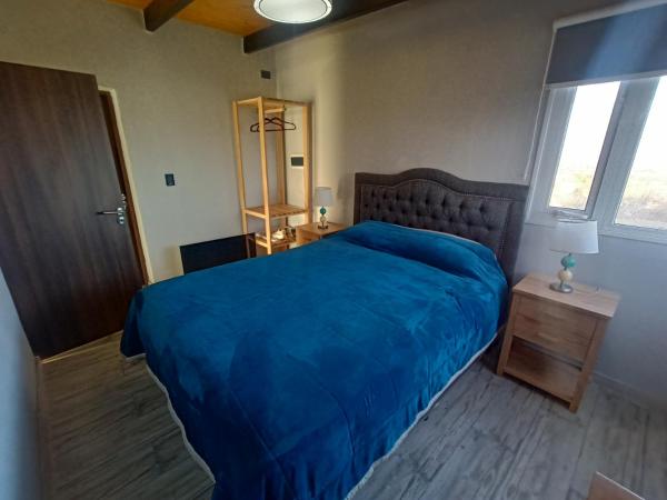 1 dormitorio con 1 cama grande y colcha azul en Crucecita Eco Lodge en Mendoza