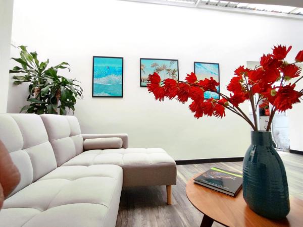 sala de estar con sofá blanco y jarrón con flores rojas en 8 Apartaestudio Cedritos independiente, en Bogotá