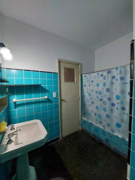 y baño de azulejos azules con lavabo y ducha. en Dpto. Luro 2 cuadras de la playa en Mar del Plata