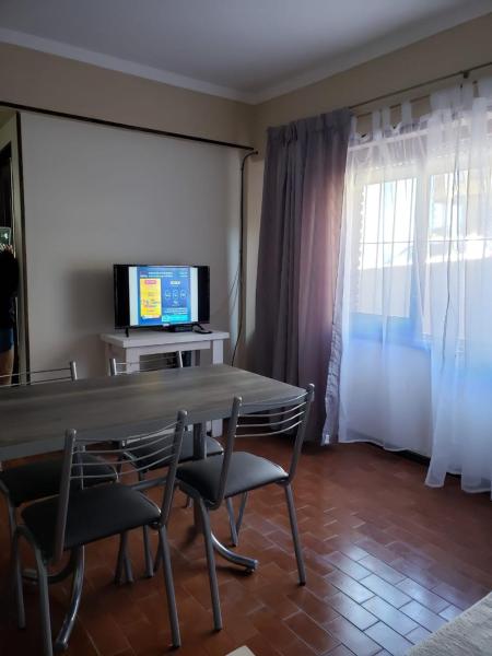 sala de estar con mesa, sillas y TV en Departamento frente al mar en Mar del Plata