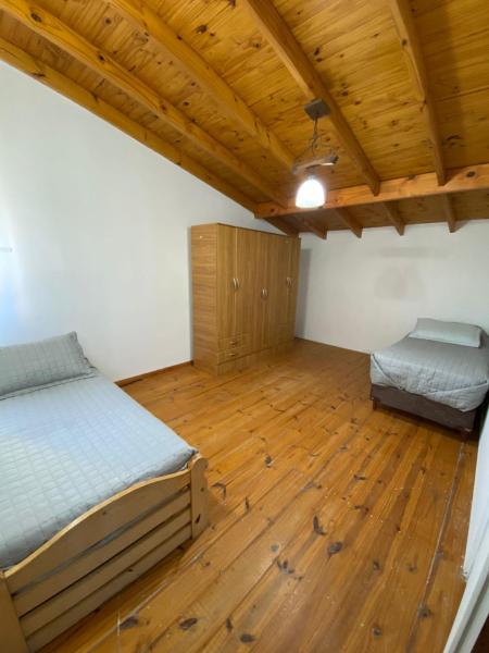 1 dormitorio con 2 camas y suelo de madera en La alegre! Hermosa casa centrica y cerca del mar en Puerto Madryn