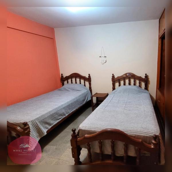 2 camas en una habitación con paredes de color naranja en Wasi Melliz en San Salvador de Jujuy