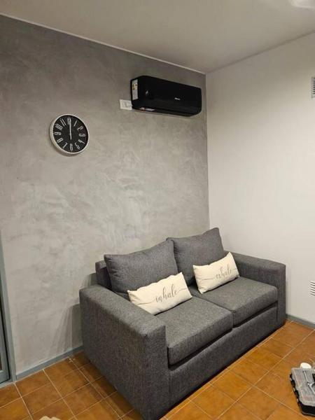 sala de estar con sofá y reloj en la pared en Exclusive Urban Apartment en Mendoza