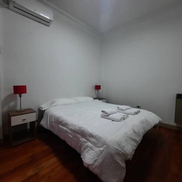 1 dormitorio con 1 cama blanca y 2 lámparas. en Departamento Plaza España con cochera en Mendoza