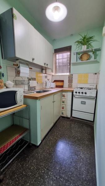cocina pequeña con armarios blancos y fogones en Depto cómodo a metros del Parque y Av. Arístides en Mendoza