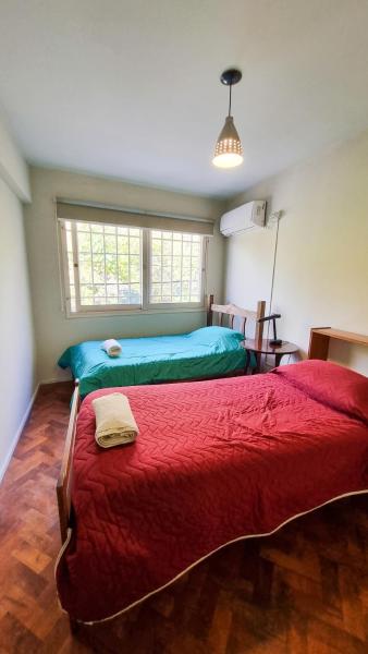 1 dormitorio con 2 camas con sábanas rojas y ventana en Depto cómodo a metros del Parque y Av. Arístides en Mendoza