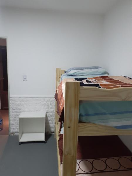 Cama en habitación con pared blanca en Casa centrica gualeguaychu 2 en Gualeguaychú
