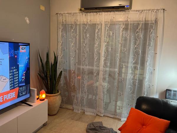 sala de estar con TV y cortina en Departamento de 3 ambientes Caballito en Buenos Aires