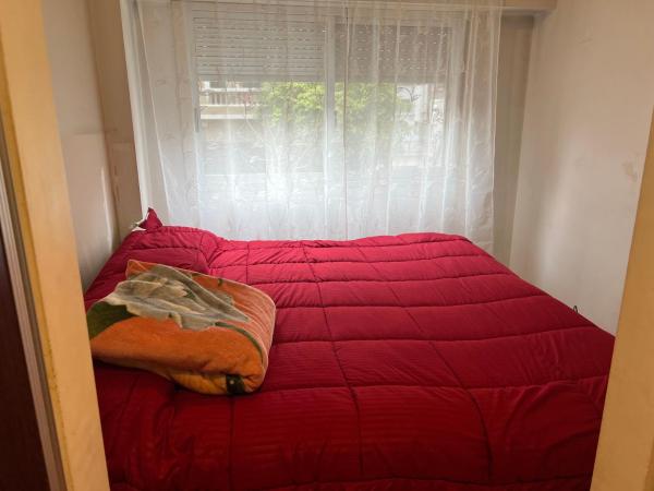 1 cama con edredón rojo frente a una ventana en Departamento de 3 ambientes Caballito en Buenos Aires