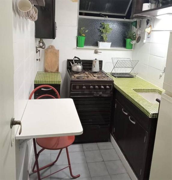 una pequeña cocina con fogones y mesa. en Departamento Muy Comodo en Excelente Zona en Buenos Aires