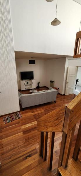 sala de estar con cama y suelo de madera en Kelly House en Mendoza